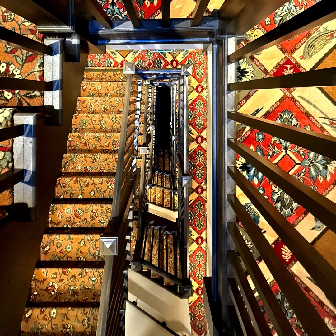 Downward shot through a stairwell covered in very ornate carpeting