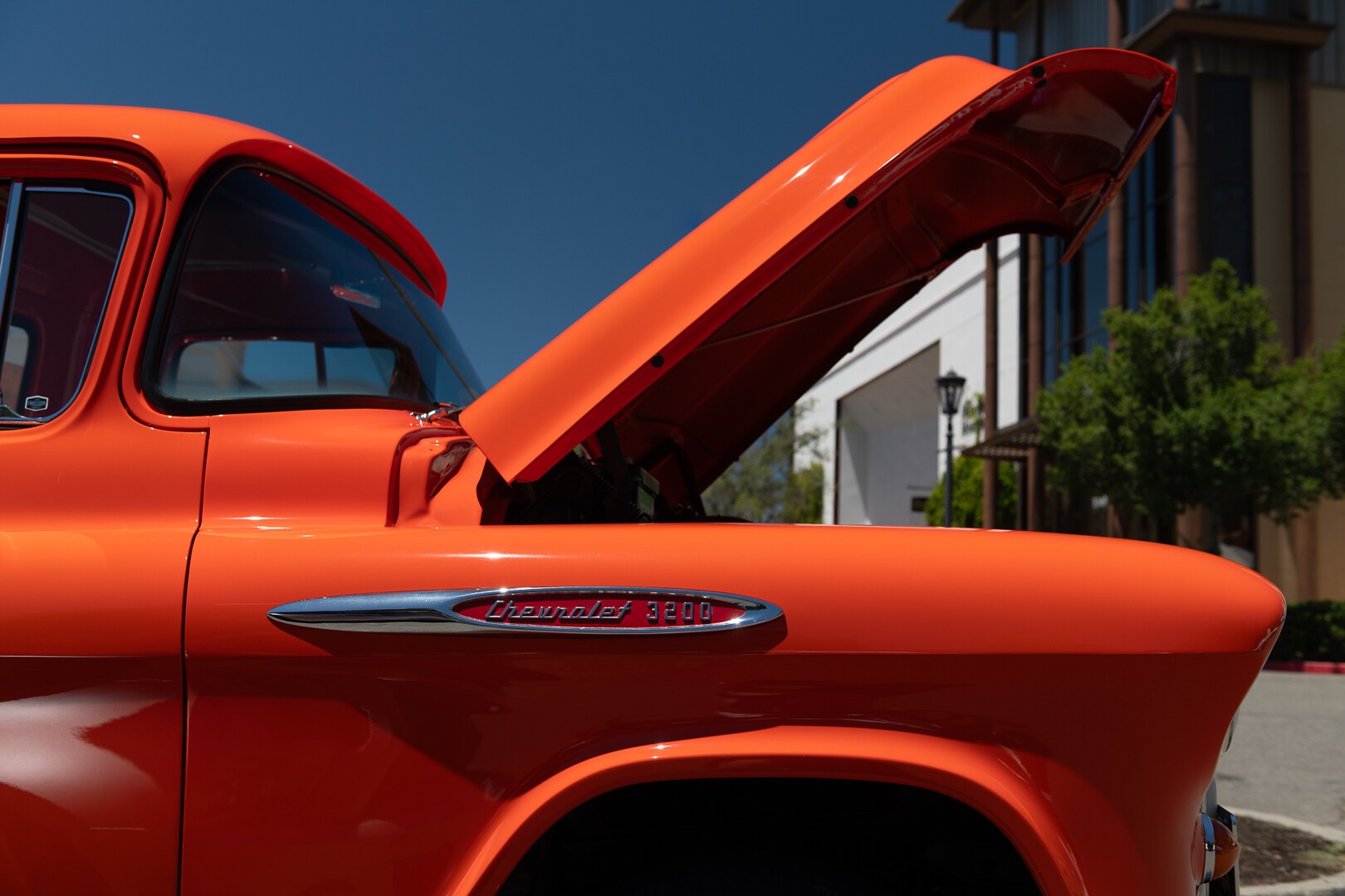 The open hood of the orange Chevrolet 3200 truck against a deep blue sky The open hood of the orange Chevrolet 3200 truck against a deep blue sky