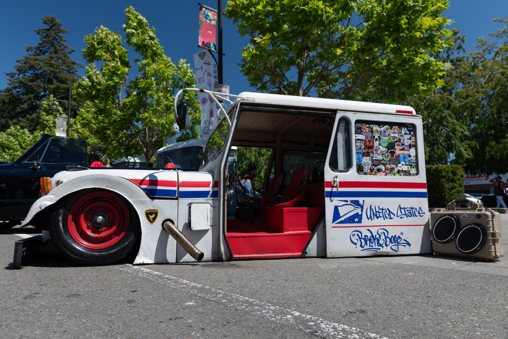 A vintage USPS delivery Jeep lowered all the way to the ground.