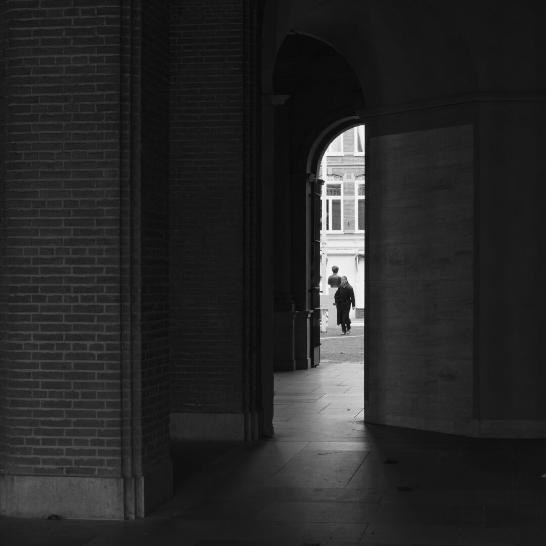 a woman walking among arches in black and white