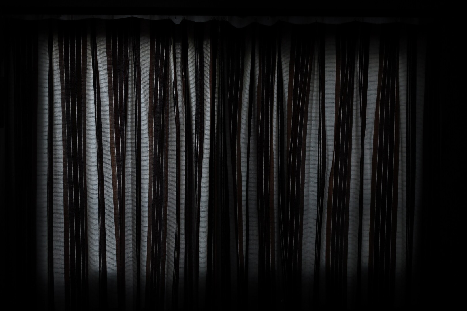 The striped curtains glow dimly in the light from outside.