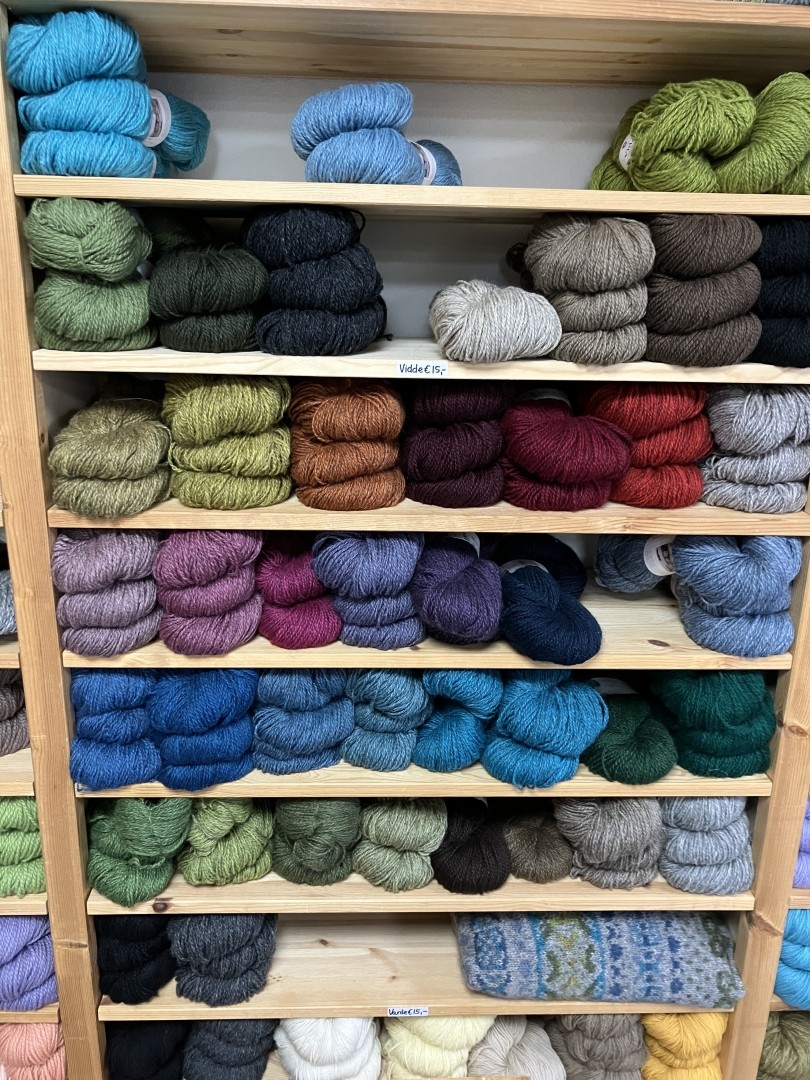 Wooden shelves with hanks of yarn in a rainbow of colours.