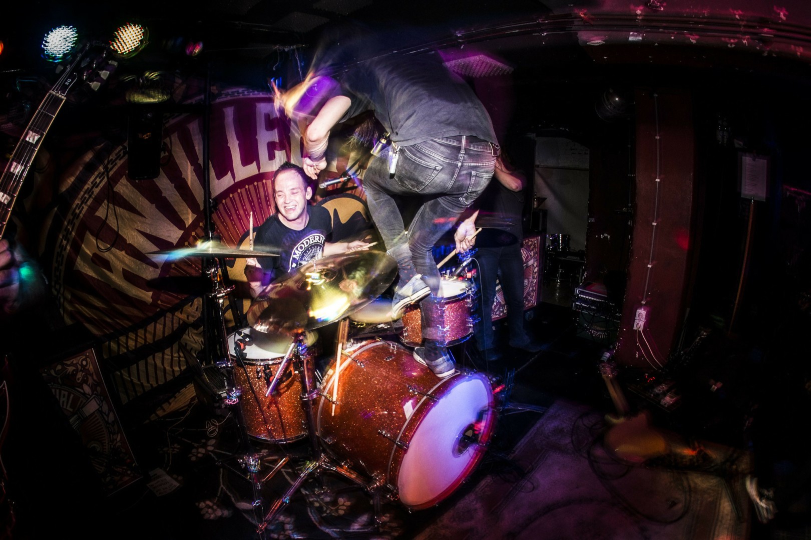 A photo of drummer Riekus behind his drumkit, hitting his floor Tom, while bassist Toon jumps of his bassdrum while hitting the high-hat with an extra drumstick.