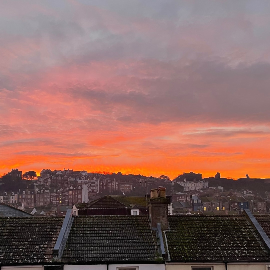 Red orange sky at dawn above the brow of a hill which is almost but not quite in silhouette