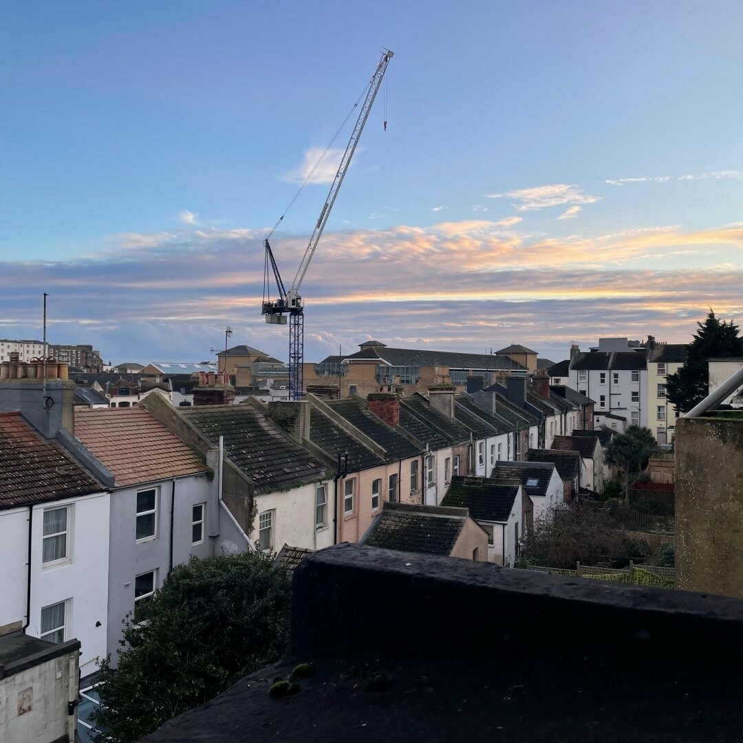 Crane against blue and grey orange dappled sky above the roofscape of Hastings