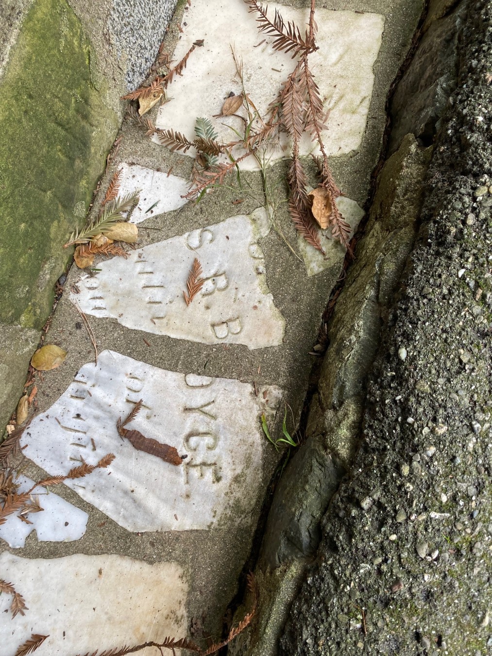 Letters on two broken pieces of gravestone: “S.B.B.” and “…OYCE.”