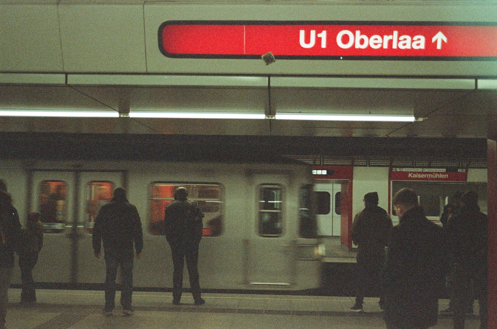 A photo of an underground train platform with metro arriving and people peopling around.