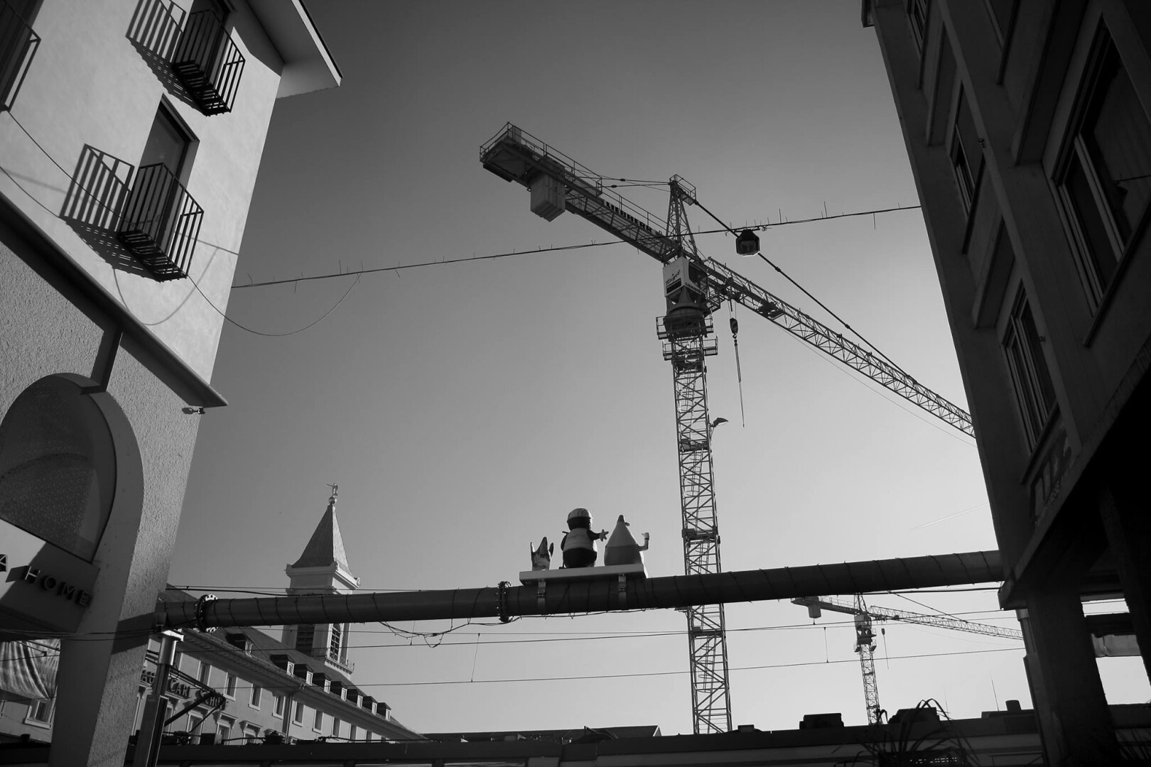 schwarz-weiß Foto von Baukran zwischen Häusern, Bodenperspektive