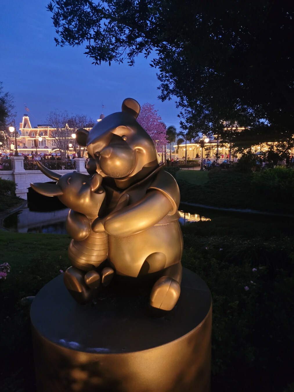 It's dusk at magic Kingdom, a spotlighted bronze statue of piglet hugging Winnie the Pooh, looking up at him in adoration. I'm melting.