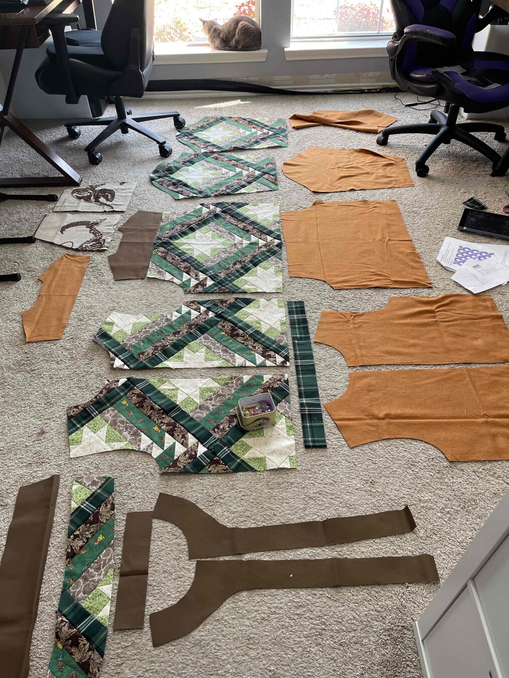 All pieces for The Camp Coat pattern by Larae Handmade lain out on the floor. 

The green and brown fabrication is the outer fabric while the orange fabric will be the lining. Outer fabrication made using the Mountain Valley quilt top pattern by Running Stitch Quilts.