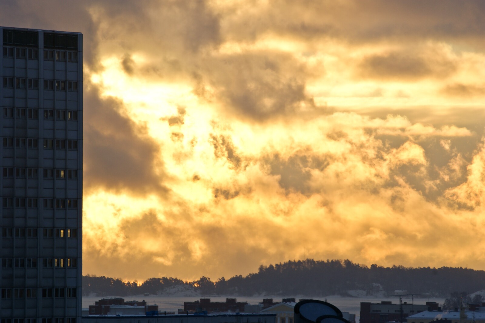 Foreground on left, a tall building, background clouds in sunrise light.