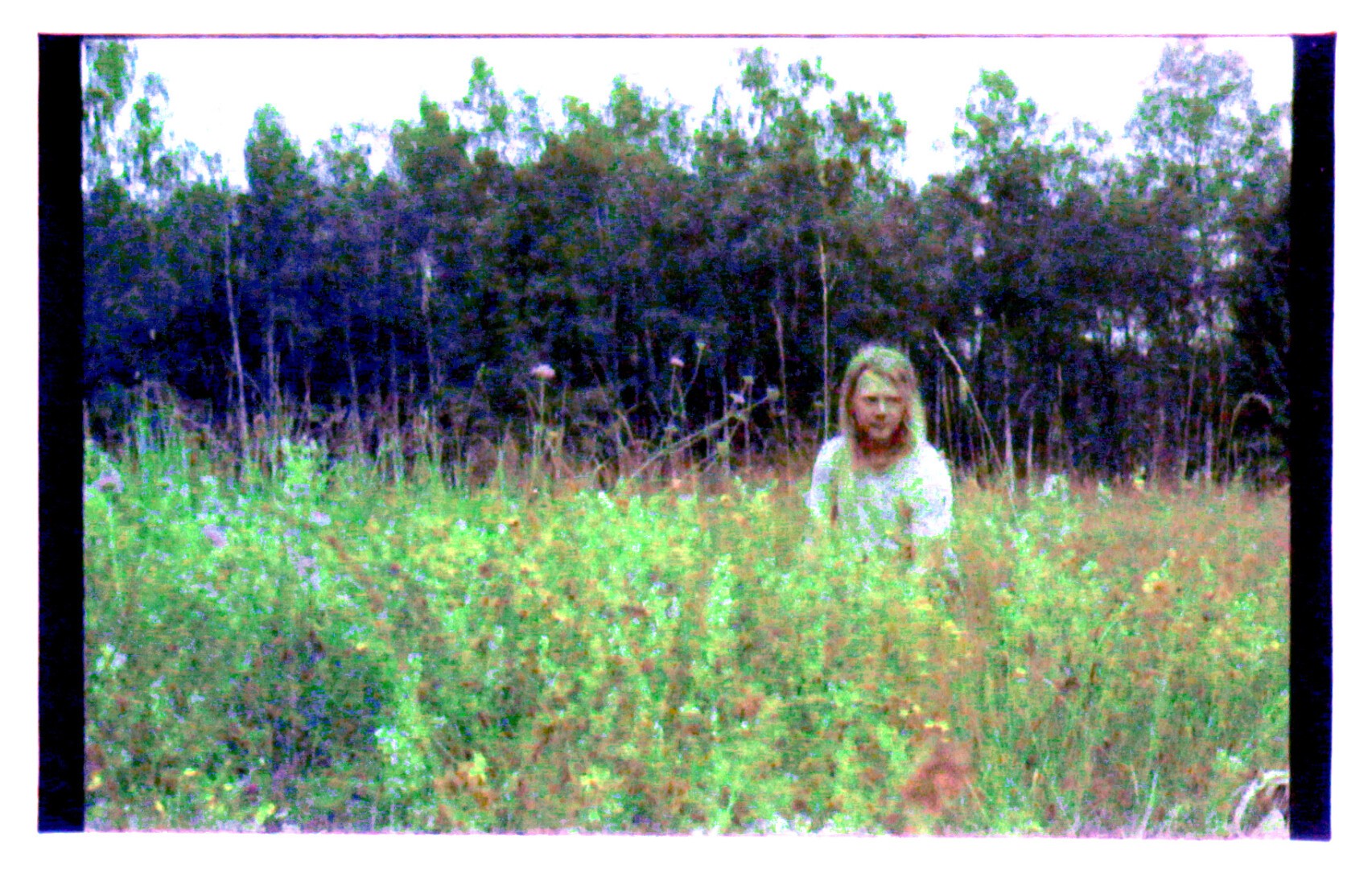 Grainy saturated image of a person sitting in a meadow full of wild flowers.