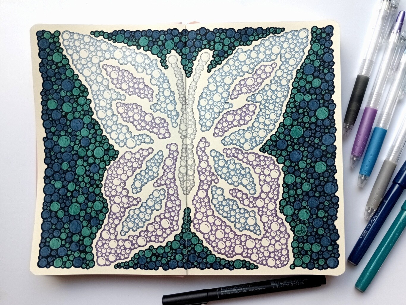 A photo of a drawing of simple bubbles grouped together creating an image of purple, blue and silver butterfly with green and blue bubbles around as a background.