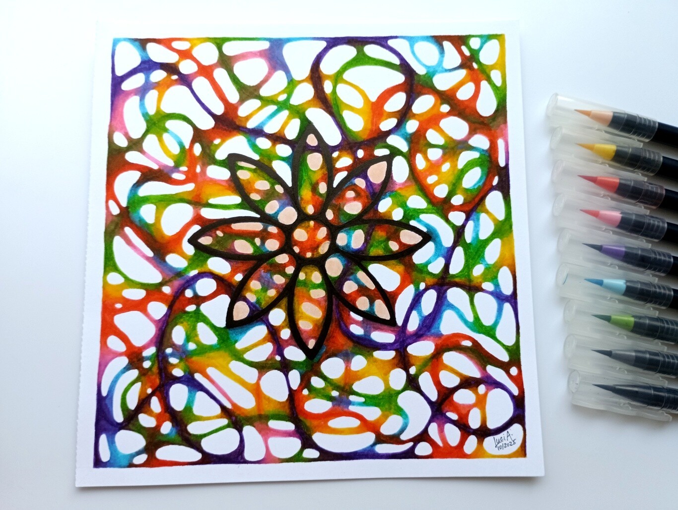 Photo of a drawing of a black flower tangled in colourful threads that are blending into each other.