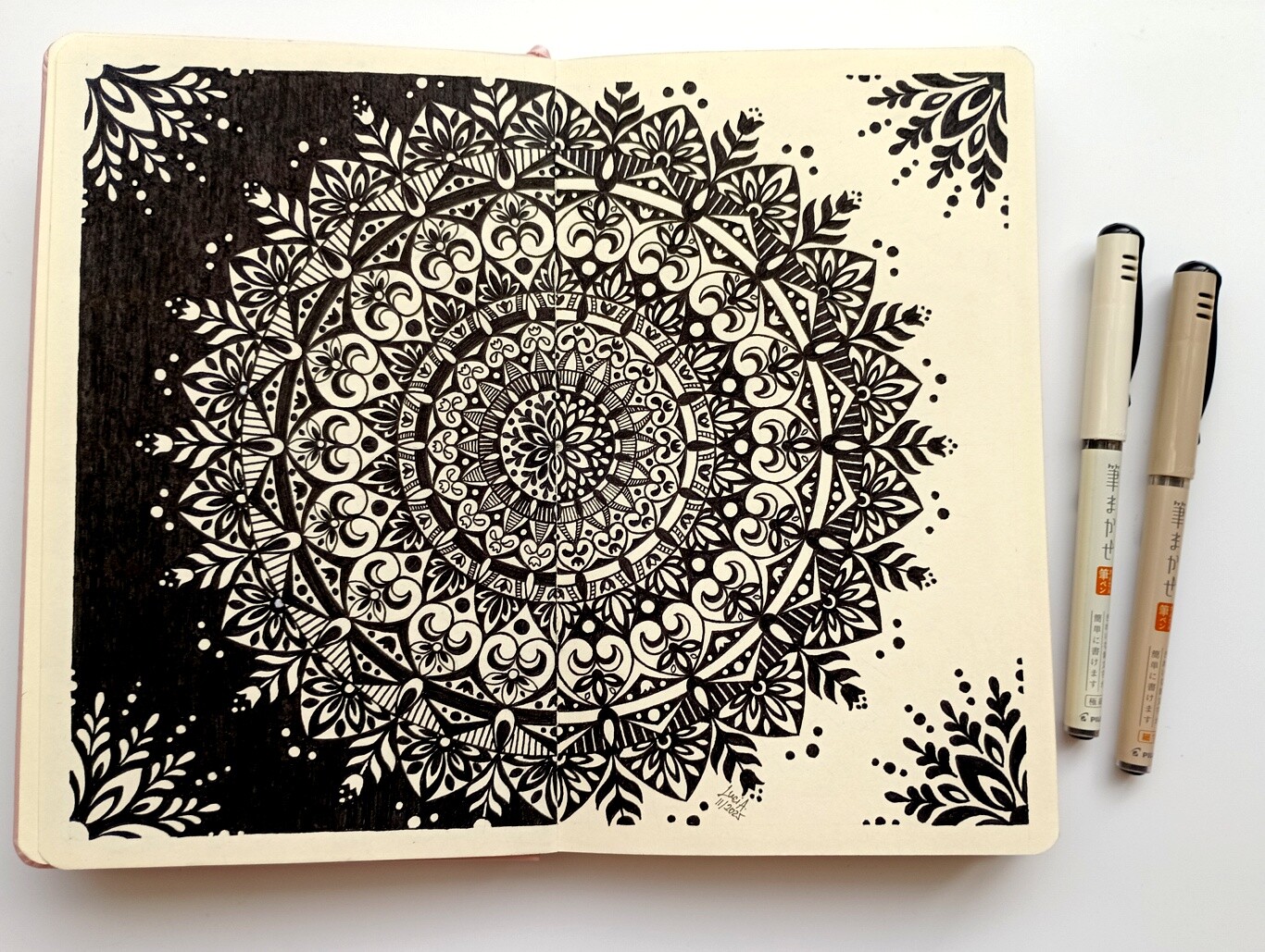 A photo of a black and white mandala with flower design and contrasting patterns on the left and right side.