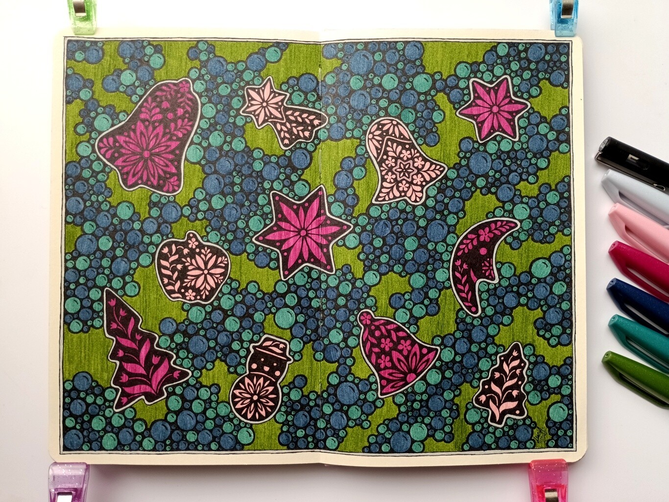 A photo of a drawing of pink Christmas shapes with floral design and green background filled with blue and blue-green bubbles grouped together.