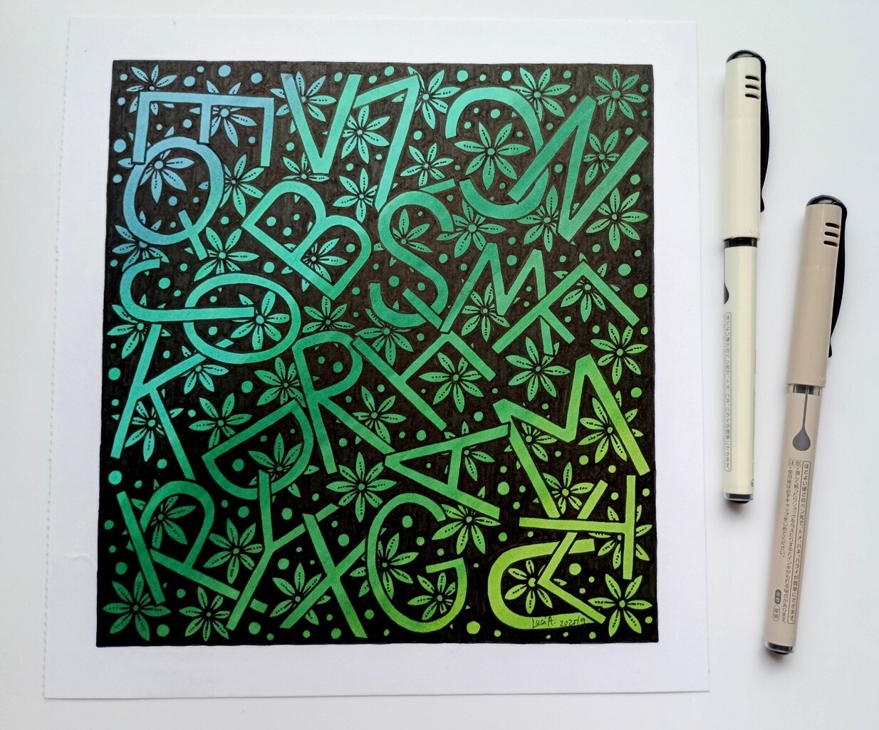 A photo of a drawing of letters and flowers with green gradients and black background.