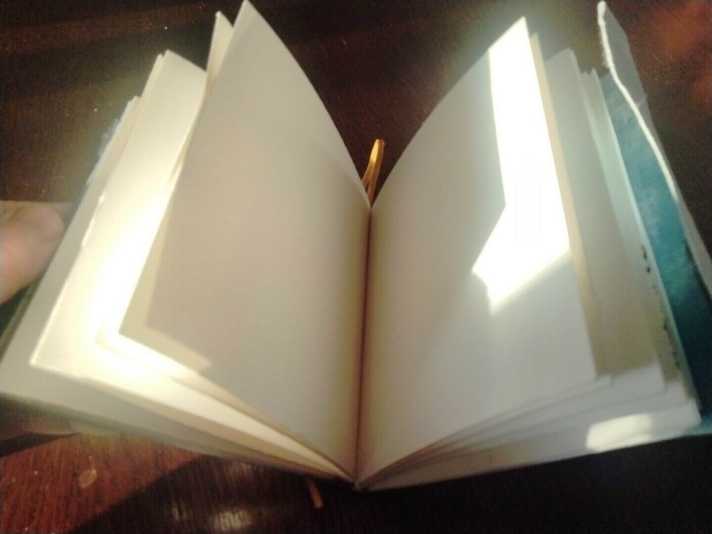 watercolor pages held in travel journal by ribbon