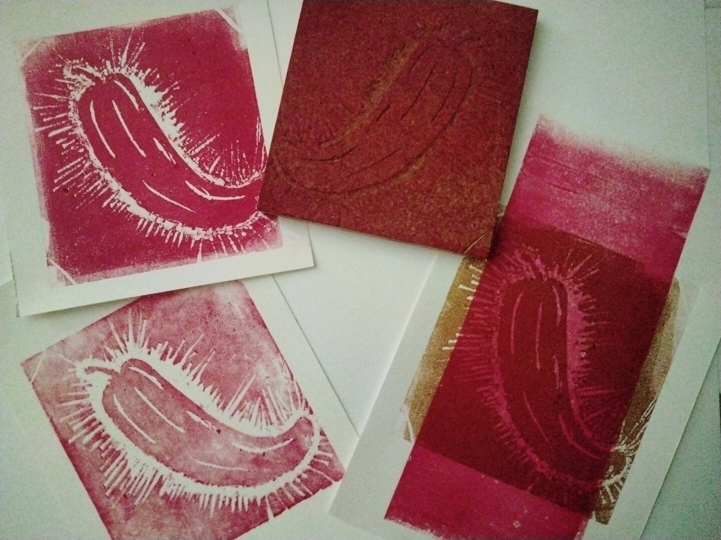 carved block of a chili and three prints from it in red