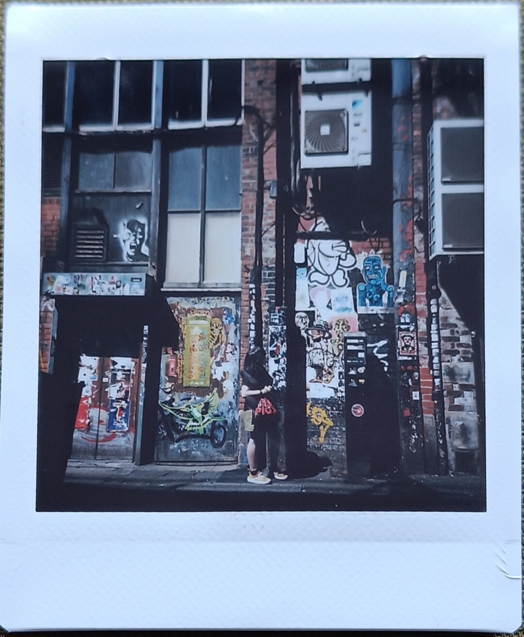 woman standing on street in front of an old building with lots of stickers and graffitis