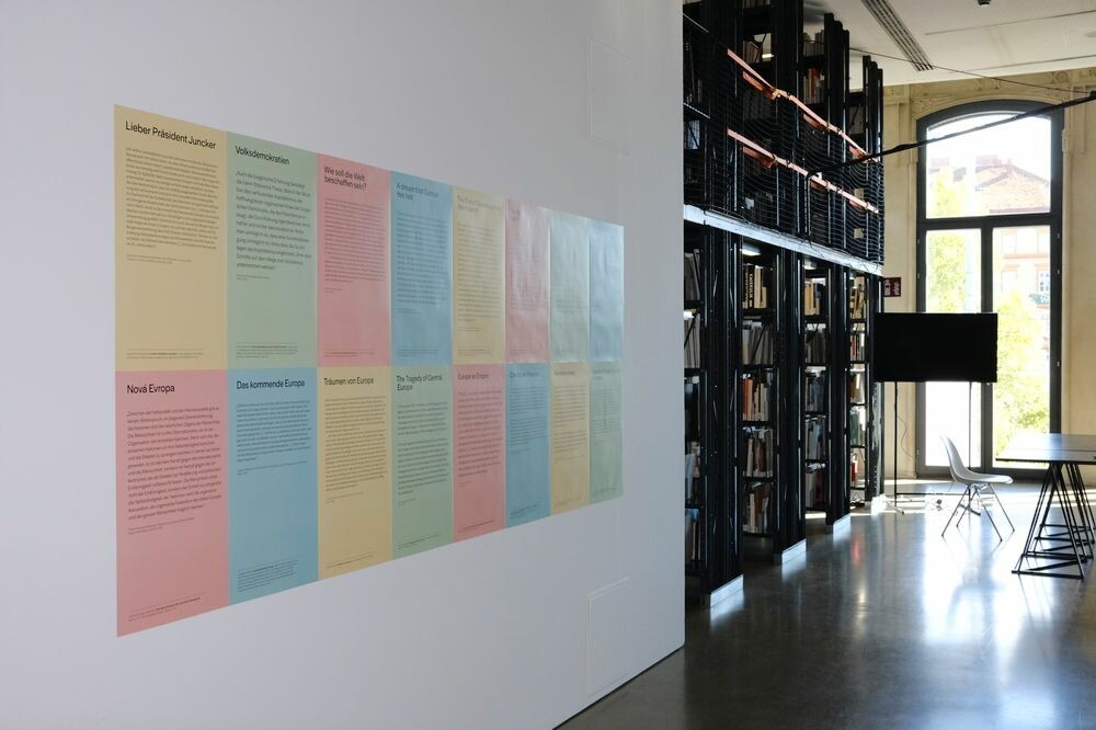 Colourful posters are hanging on a wall in a library.