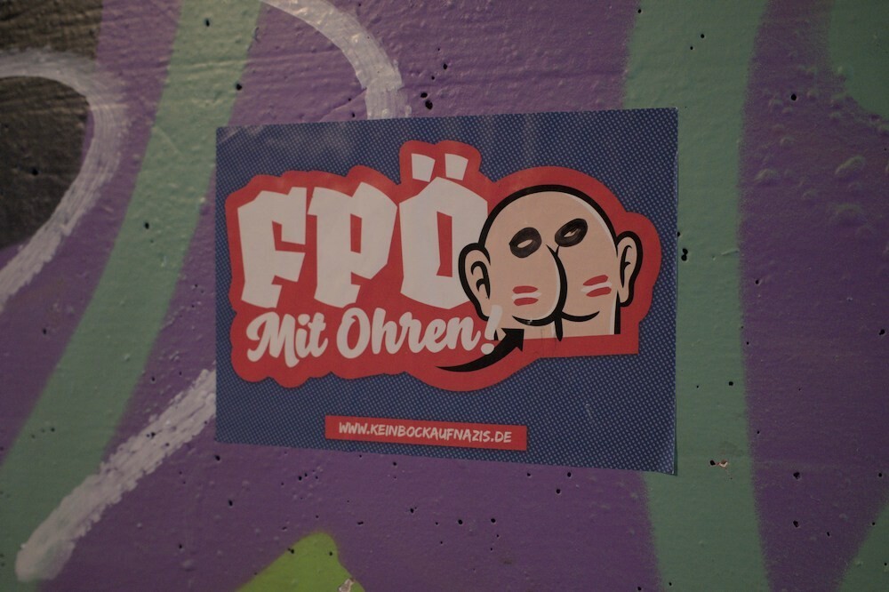 A sticker shows an arse with ears and the words "FPÖ mit Ohren".