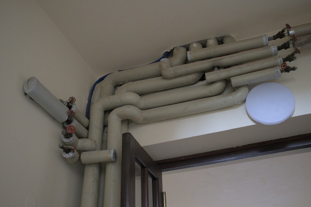 Pipes run underneath the ceiling in an old building.