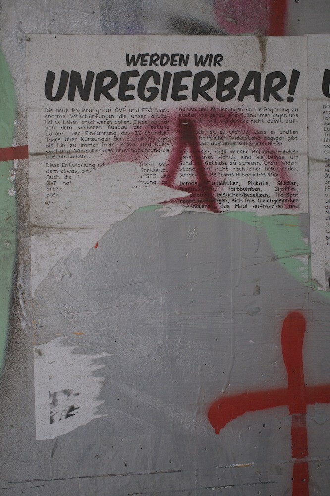 "We become ungeovernable" stands on a poster that was ripped apart.